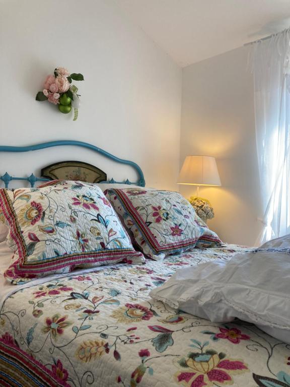 1 cama con colcha floral y almohadas en un dormitorio en Les Magnolias, en Montbrun-les-Bains