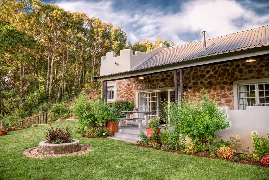 a stone house with a garden in front of it at Trout Escape Farm in Dullstroom