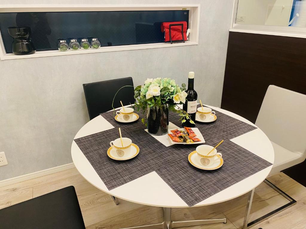 a white table with plates and a vase of flowers at Love House in Osaka