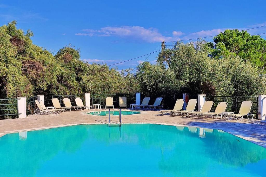 a swimming pool with lounge chairs and a bunch ofitures at Nissaki Sea View Apartments in Nisakion