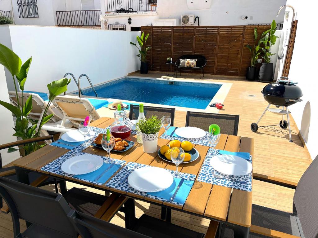 una mesa con platos y fruta delante de una piscina en Nerja Paradise Rentals - Villa Topaz, en Nerja