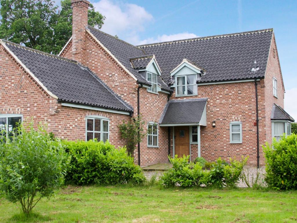 a brick house with a black roof at Heckingham Manor in Loddon