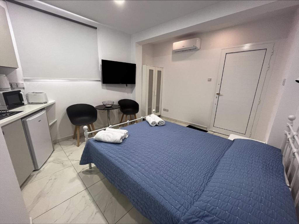 a bedroom with a blue bed and a kitchen at Jacks Apartment in Paphos City
