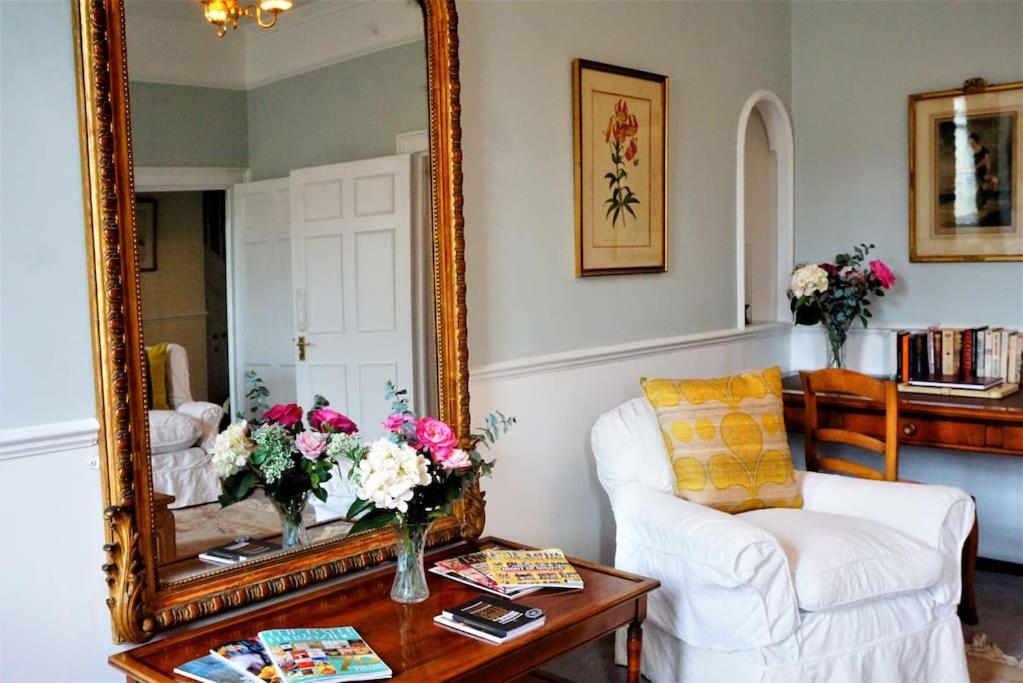 ein Wohnzimmer mit einem Spiegel und einem weißen Stuhl in der Unterkunft Great Pulteney St. Maisonette (parking) in Bath