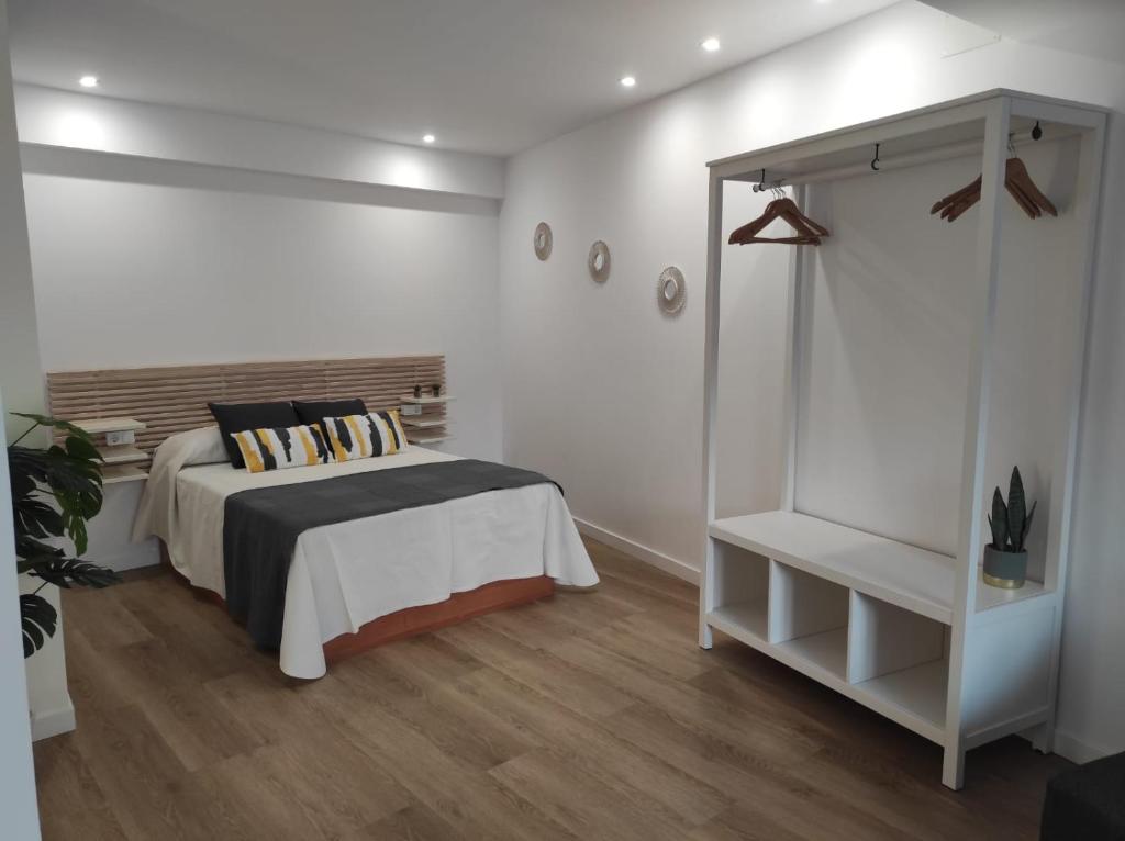 1 dormitorio con cama y pared blanca en Apartamentos turísticos Demar, en O Grove