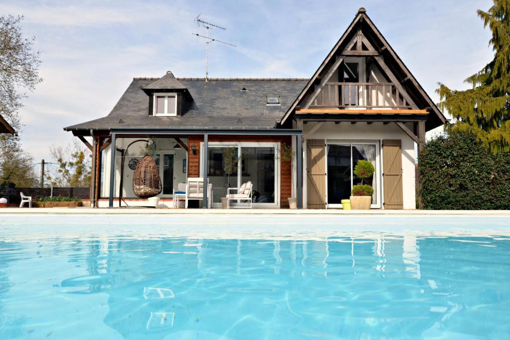 a house with a swimming pool in front of a house at La Belle Rochette in Bouessay