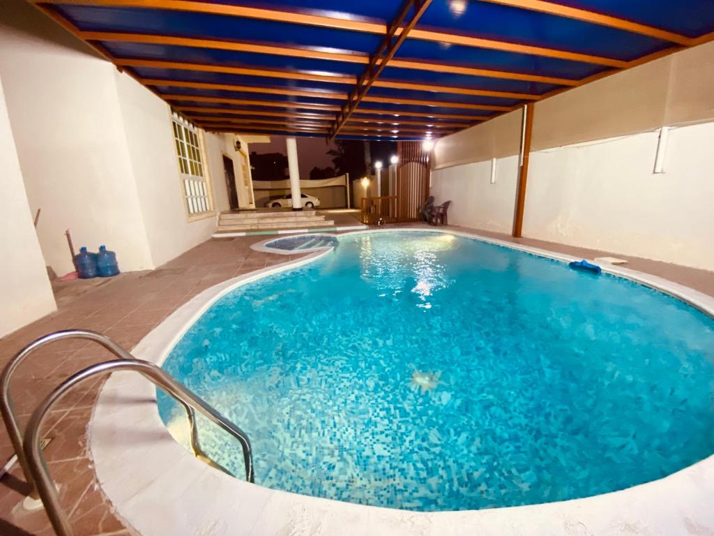 a large pool with blue water in a building at Private Cottage in Sharjah