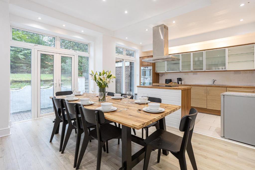 a kitchen and dining room with a wooden table and chairs at Pillo Rooms - Spacious 4 Bedroom Detached House close to Heaton Park in Manchester