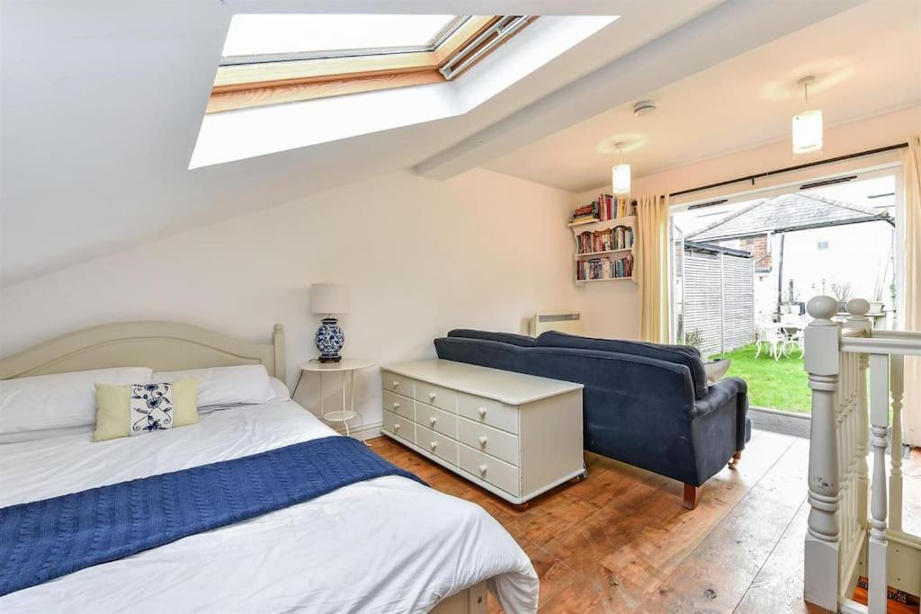 a bedroom with a bed and a couch and a window at Garden room, central Winchester in Winchester