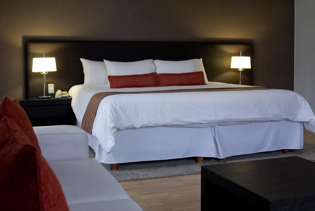 a bedroom with a large white bed with red pillows at Amérian Cordoba Park Hotel in Córdoba