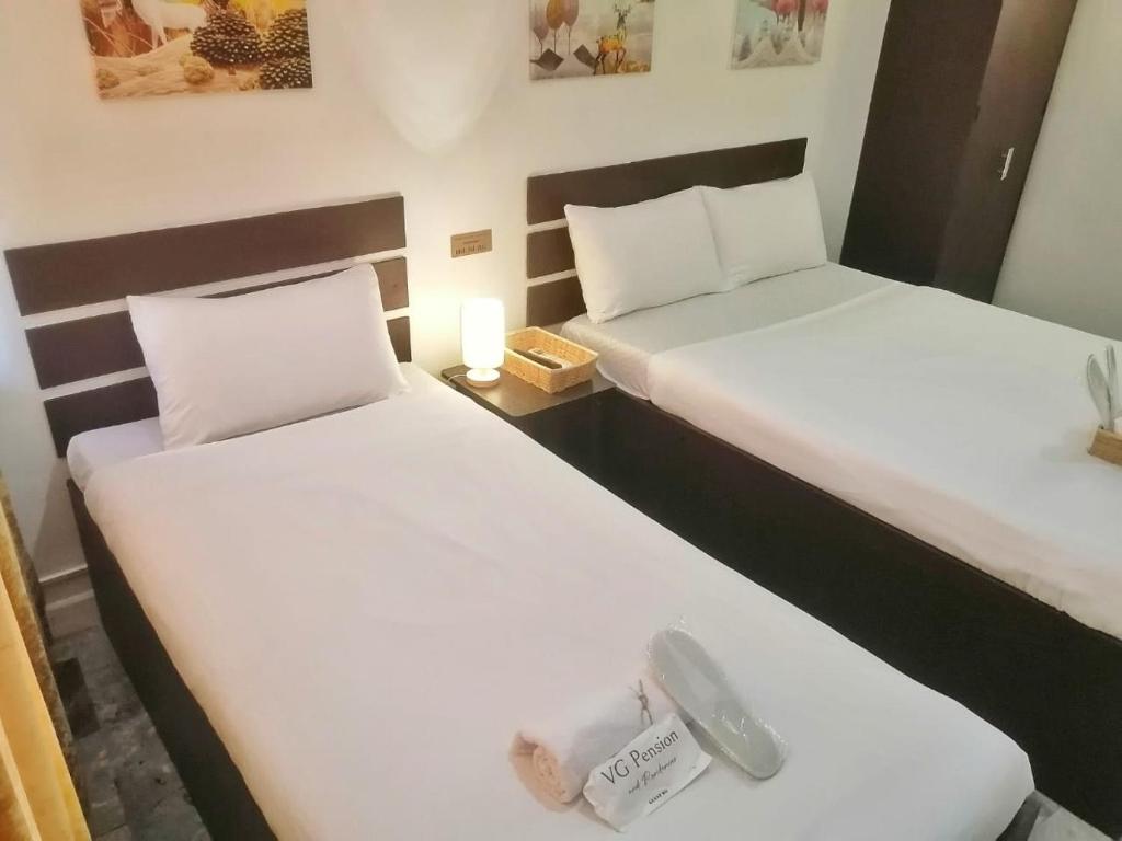2 Betten in einem Hotelzimmer mit Preisschild in der Unterkunft VG Pension & Residences in Adlawon