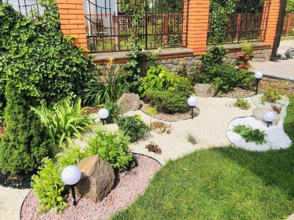 un jardin avec des rochers et des plantes devant une maison dans l'établissement Julia, à Ouman