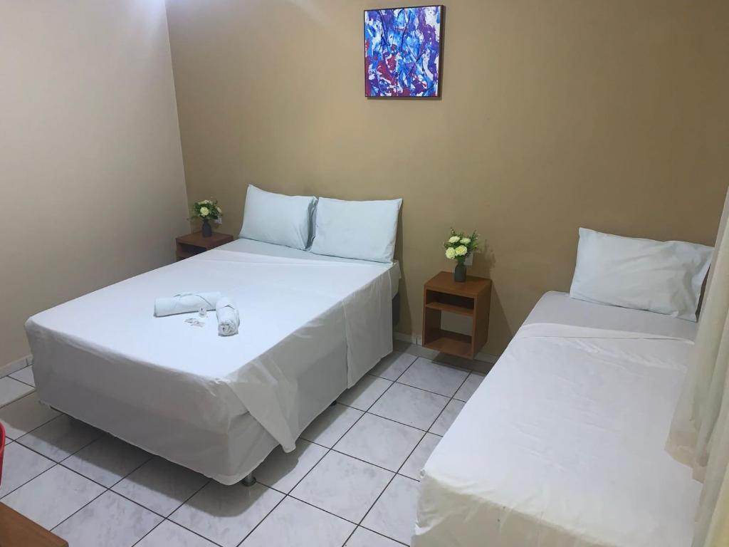 2 camas en una habitación con sábanas y almohadas blancas en Hotel Sambaquis en São Luís