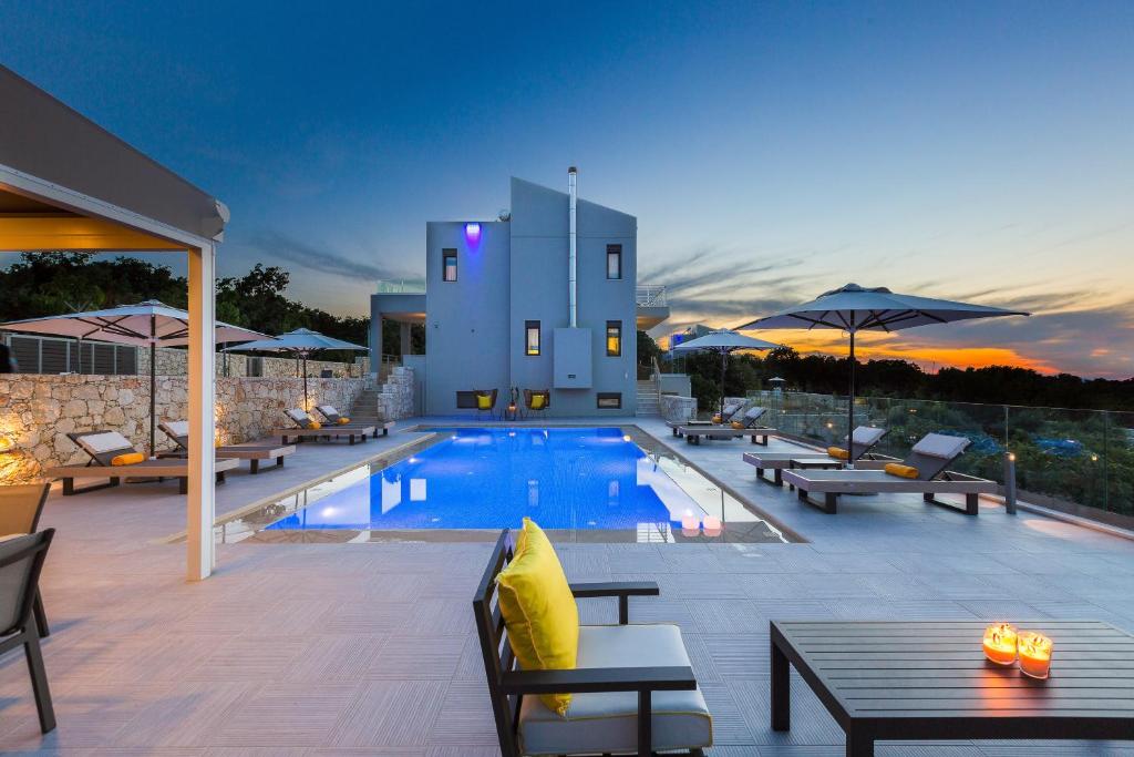 una piscina con mesas y sillas y un edificio en Luxury Cretan Villas with private pools, en Gállos