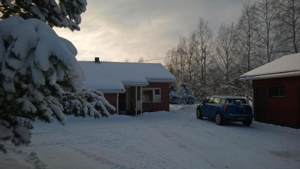 un coche azul estacionado frente a una casa cubierta de nieve en Eric Apartment, en Vampula