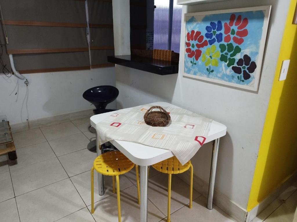 una mesa blanca con dos sillas amarillas y una pintura en Flat Aconchegante na Asa Sul, en Brasilia