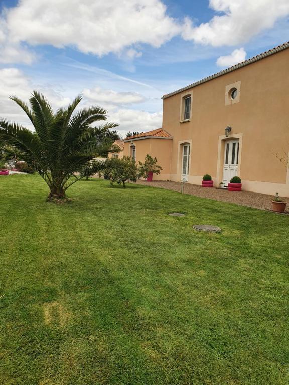 une maison avec un palmier dans la cour dans l'établissement Le logis du marais, à Les Magnils-Reigniers