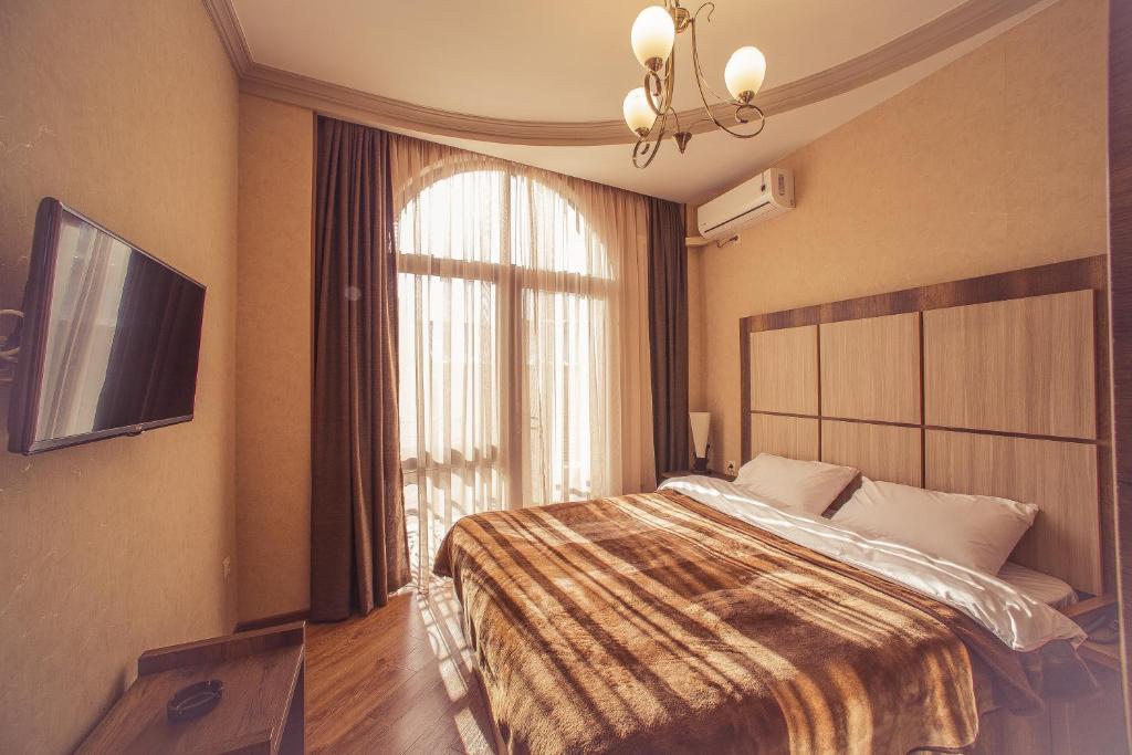a bedroom with a bed and a large window at Royal Venezia Hotel in Batumi