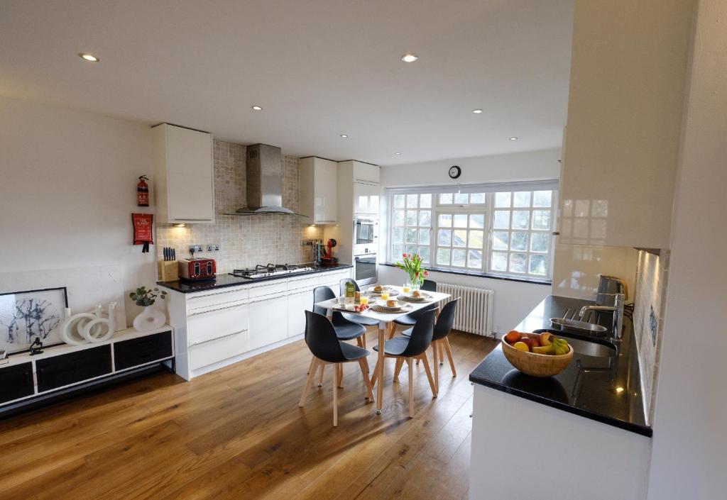 a kitchen with white cabinets and a table with chairs at Riverwalk Apartment North in Datchet