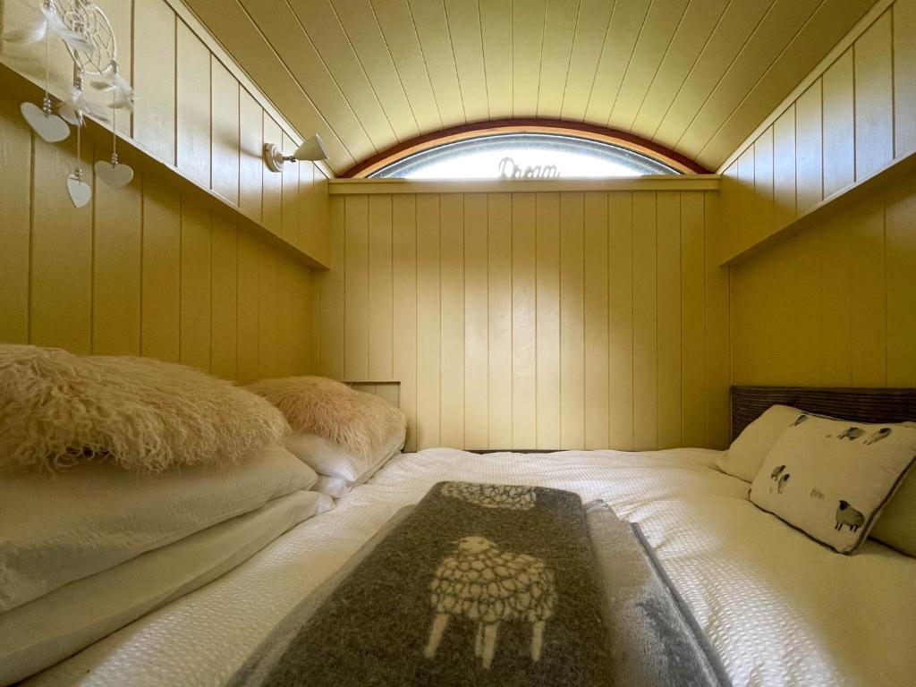 a bedroom with two beds in a room with a window at 5 Star Shepherds Hut in Betws y Coed with Mountain View in Capel Curig