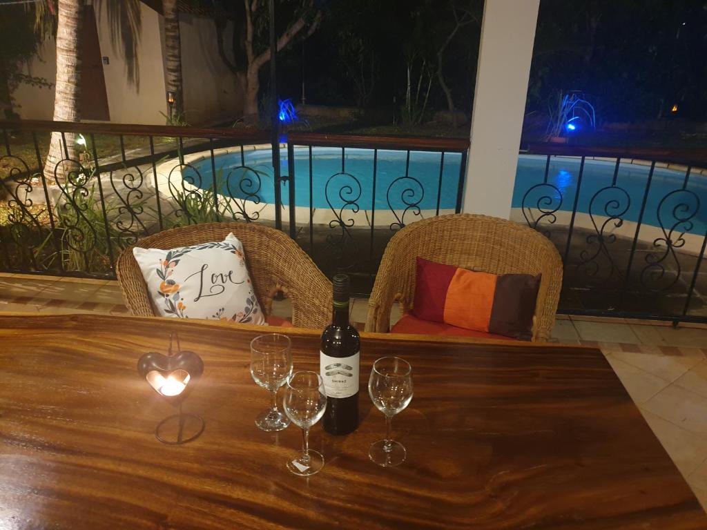 una botella de vino sentada en una mesa con copas de vino en Secluded luxury villa with pool views privacy en Rivière Noire