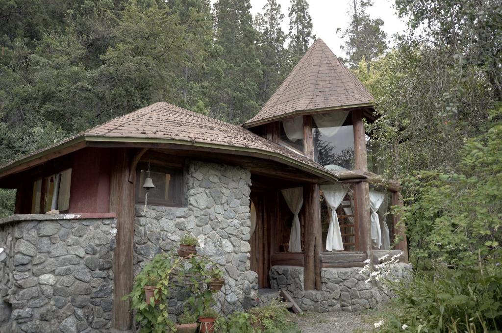un piccolo edificio in pietra con una torre in cima di Cabaña Las Tejas a El Bolsón