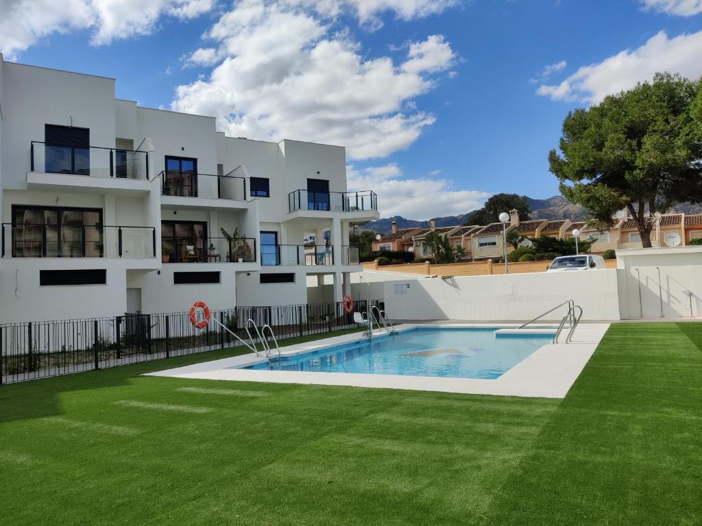 a building with a swimming pool in front of a yard at Benalmadena new terraced house 3 bedroom 2,5 bathroom in Benalmádena