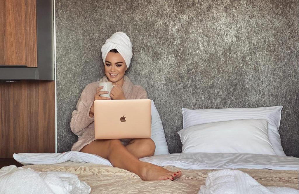 kobieta siedząca na łóżku z laptopem w obiekcie Villa Miss w mieście Bogatić