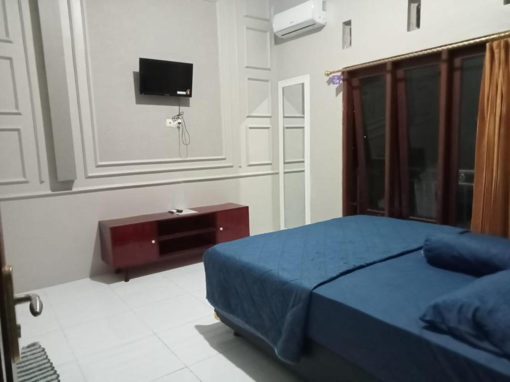 a bedroom with a blue bed and a tv at Cahaya Homestay in Magelang