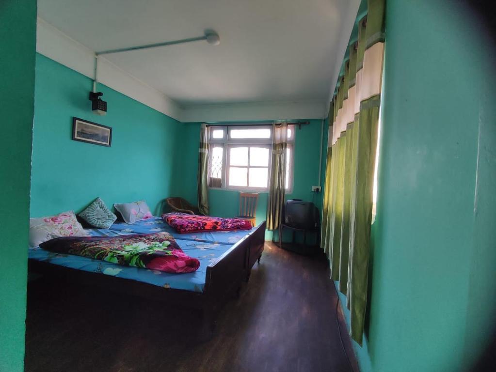 a room with two beds with blue walls and a window at Hotel Gaurav in Darjeeling