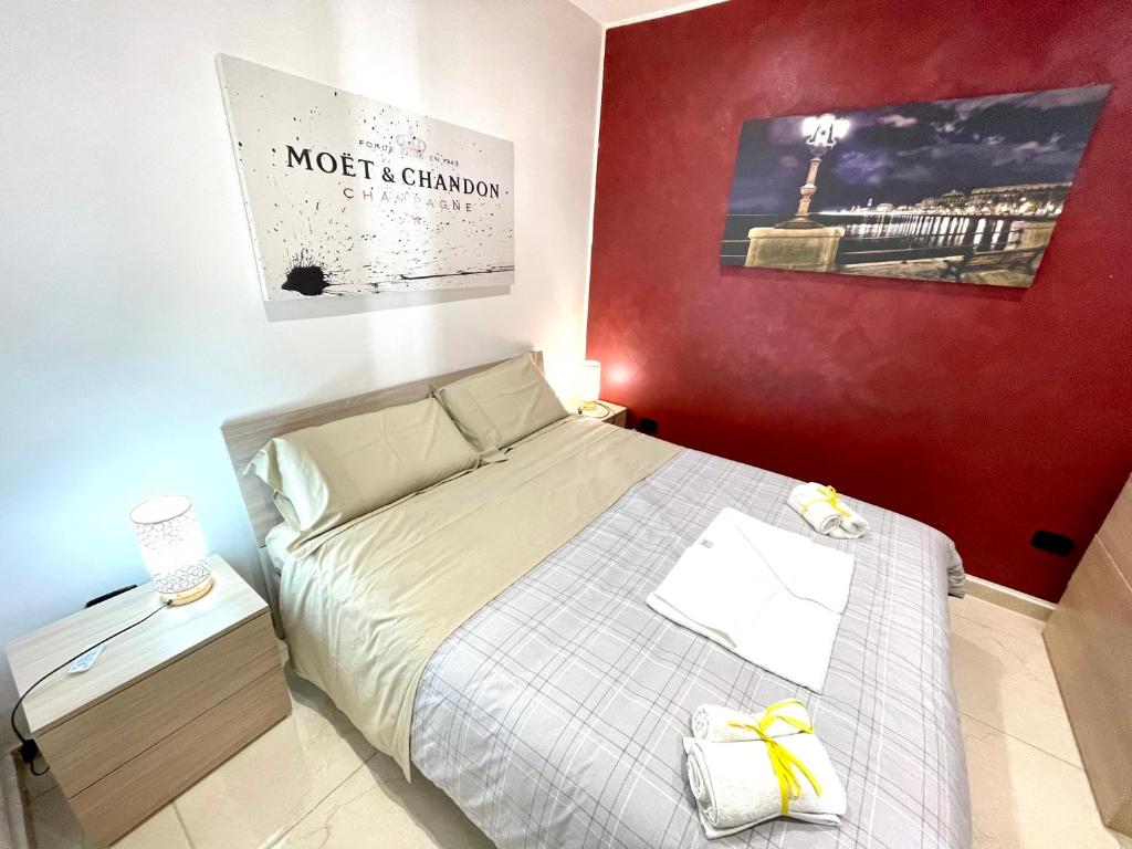 a small bedroom with a bed and a red wall at B&B Romeo in Bari