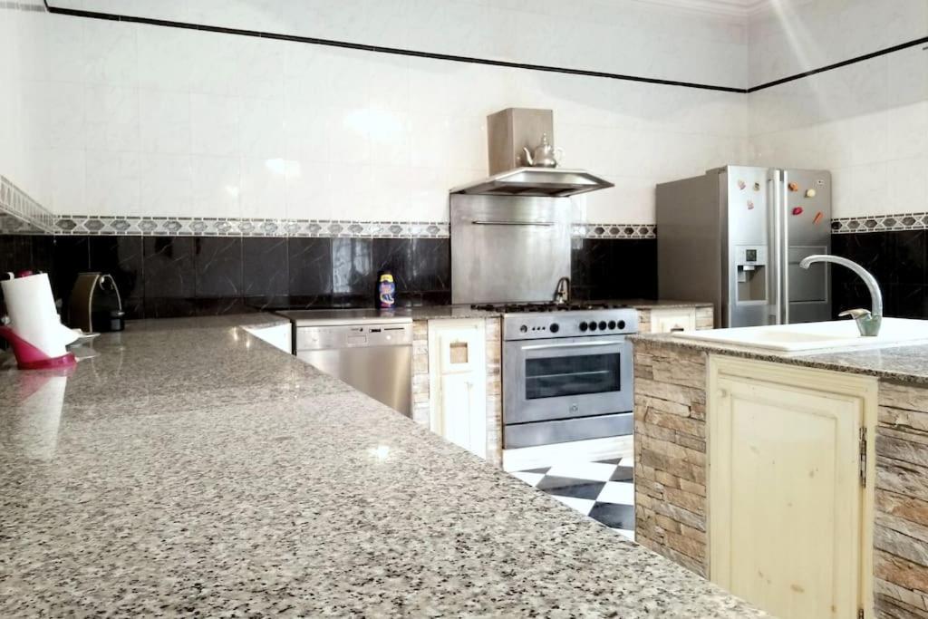 a large kitchen with a counter top and appliances at Appartement 200 m 2 + 5 min du c.c.o in Oran