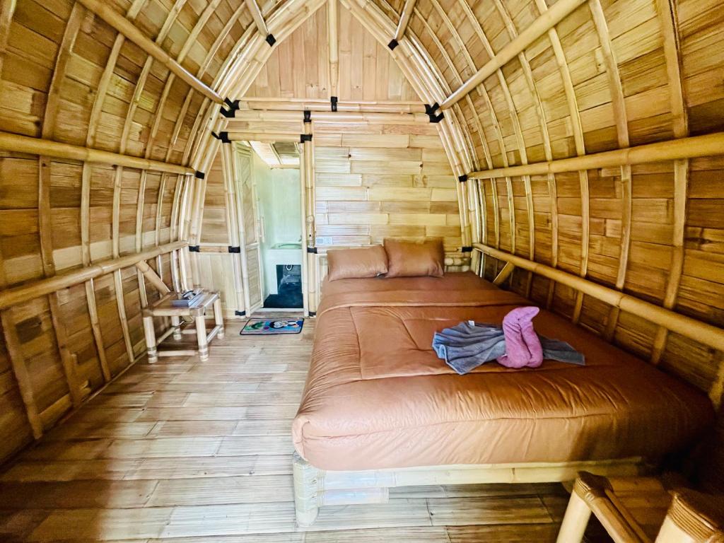 Cama grande en habitación con paredes de madera en Bamboo Austin Mountbatur, en Baturaja