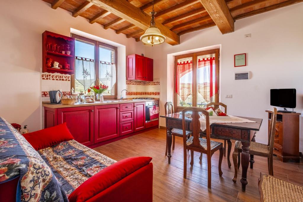 eine Küche mit roten Schränken und einem Tisch im Zimmer in der Unterkunft Appartamento Rosso - Monte Crespini in Manciano