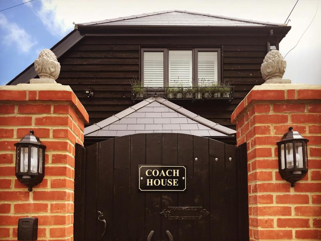 a black house with a black gate and a sign on it at The Coach House in Whitstable