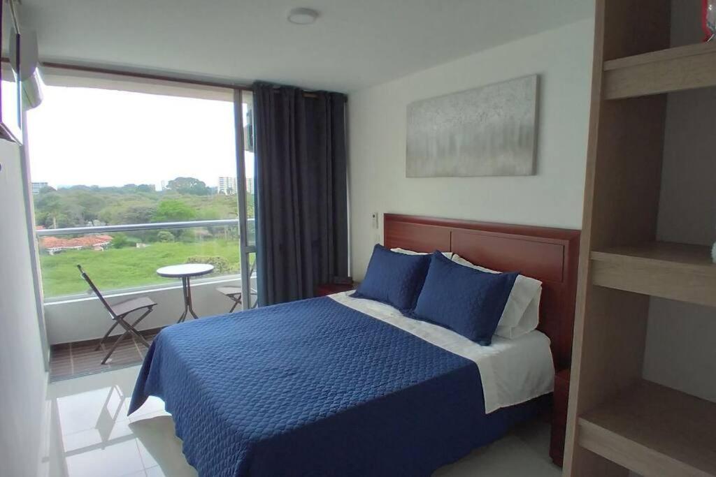 a bedroom with a blue bed and a large window at Hermoso Apartamento Ricaurte Peñazul La Morada. in Ricaurte