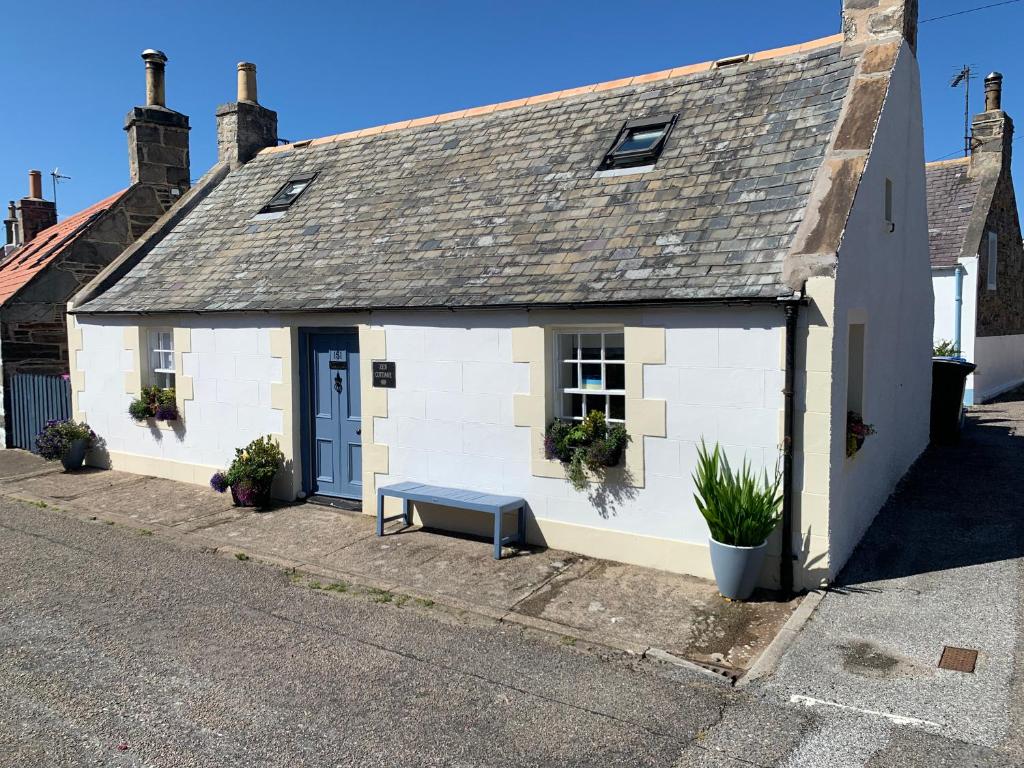 a white building with a bench in front of it at Zen Cottage Seatown Cullen in Cullen