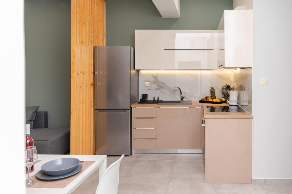 a kitchen with white cabinets and a stainless steel refrigerator at P&K LUXURY APARTMENTS 1 in Kalamata