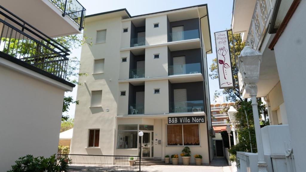ein Apartmentgebäude mit einem Schild, das den Weg zur Villa im Kasten liest in der Unterkunft B&B Hotel Villa Nora in Bellaria-Igea Marina
