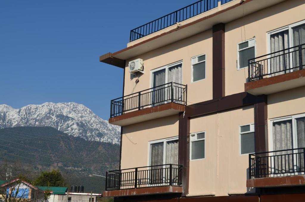 a building with balconies and a mountain in the background at HIMALAYA INN in Pālampur