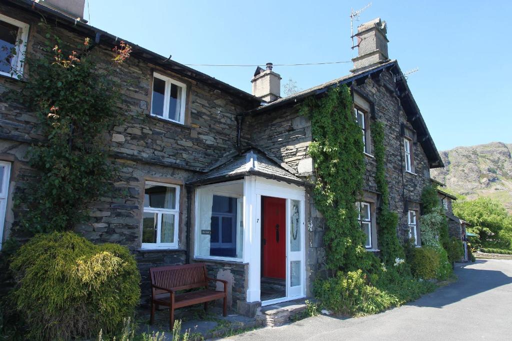 an old stone house with a red door at Rose Bank Cottage Coniston in Coniston