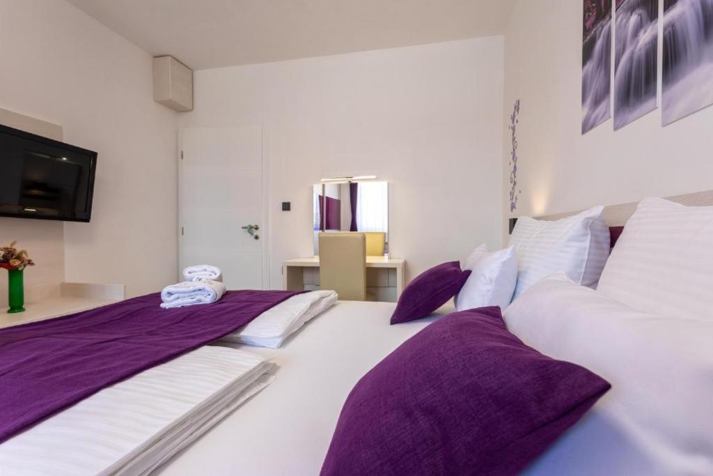 a bedroom with two beds with purple and white pillows at Apartman Naomi in Krk