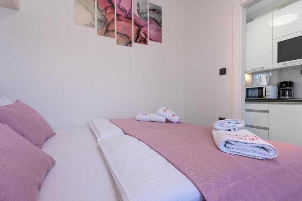 a white bed with two towels on top of it at Apartman Naomi in Krk