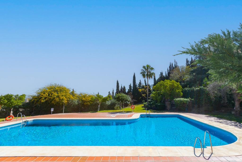 Una gran piscina azul con árboles al fondo. en Casa Buda, en Torrequebrada