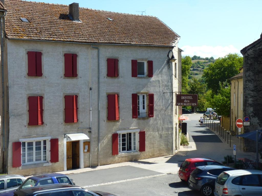 an old building with red shutters on a street at Hôtel Restaurant des Voyageurs in Nant