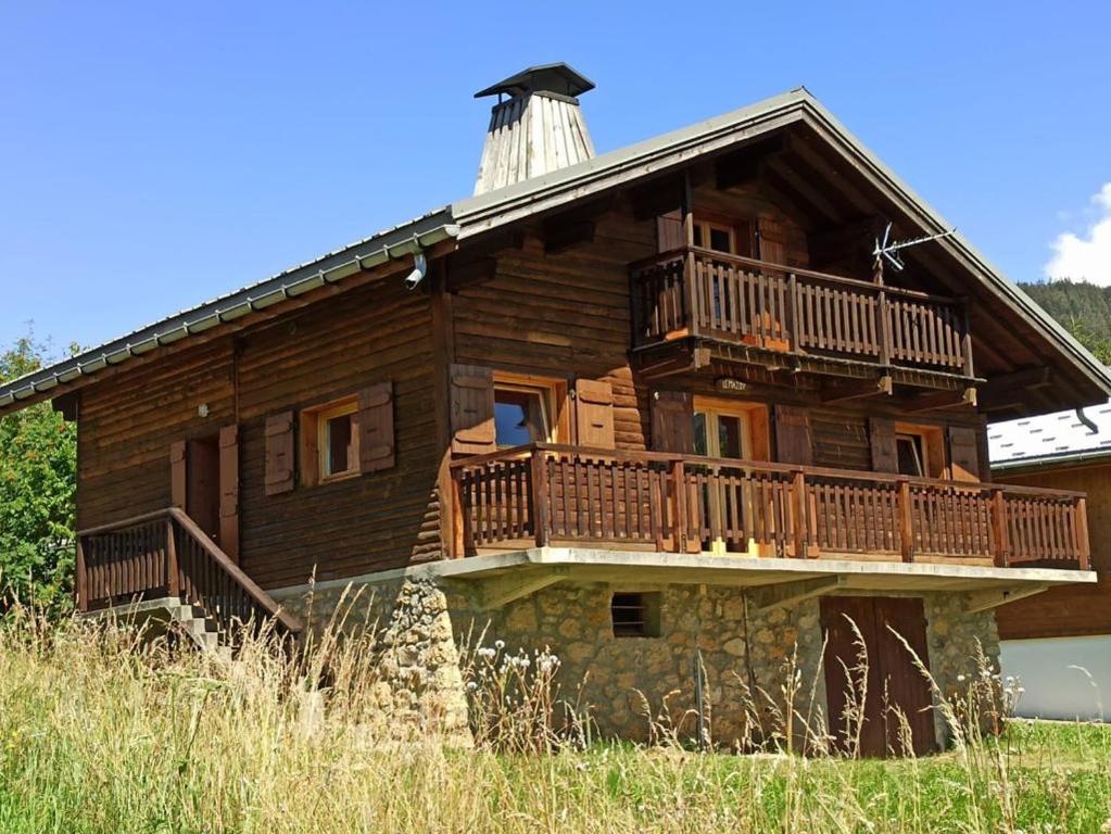 Casa de madera grande con balcón en la parte superior en CHALET FAMILIAL AU PIED DES PISTES ET COMMERCES, en Cohennoz