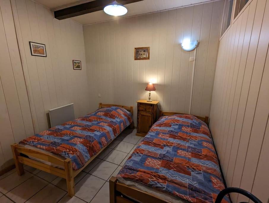 two twin beds in a room with a table at Gîte Elisa in Vals-les-Bains