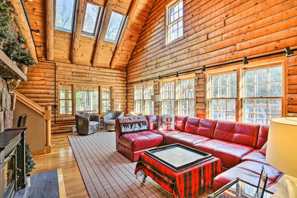 a living room with a red couch in a log cabin at Accord Vacation Rental with Pool and Hot Tub! in Accord