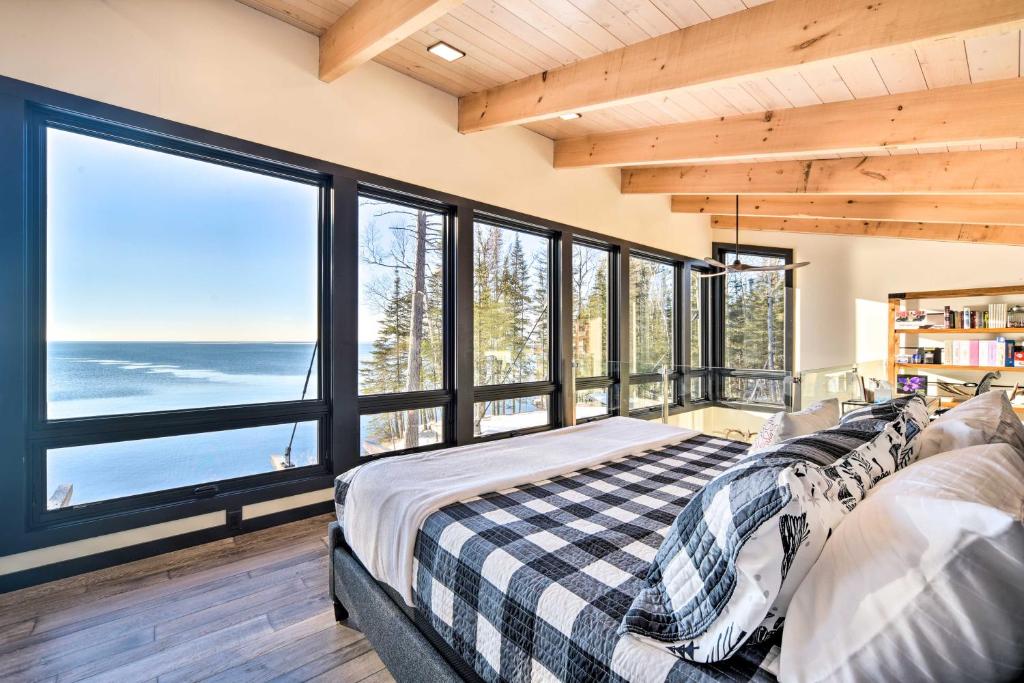 een slaapkamer met een bed en grote ramen bij Waterfront Cabin on Lake Superior with Fire Pit in Two Harbors