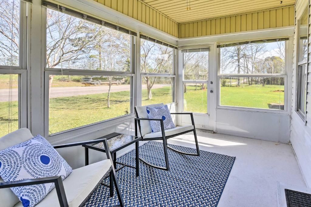 - deux chaises et une table sur une terrasse couverte avec fenêtres dans l'établissement Peaceful Southern Countryside Escape with Porch, 